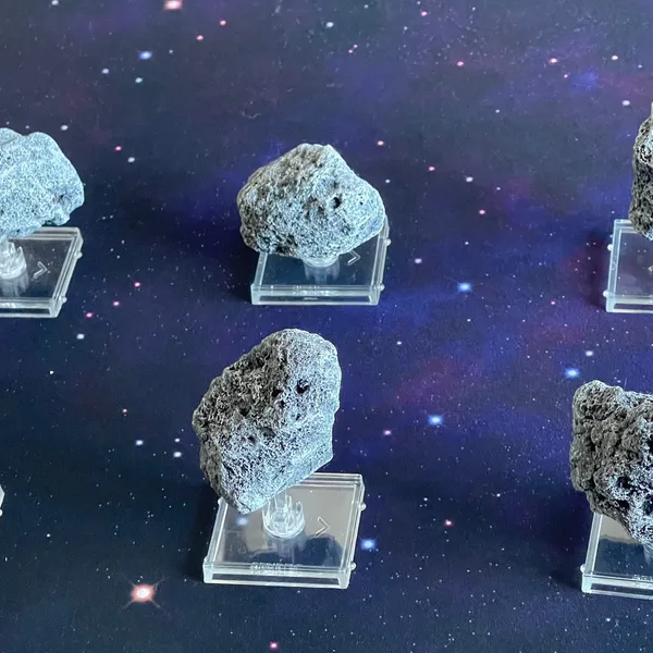 All six painted asteroid miniatures on their clear flight stands against a starfield.