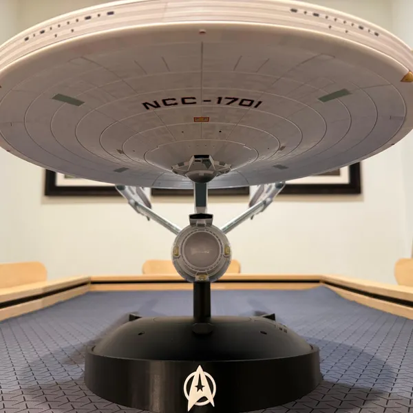 A TOMY 1/350 Enterprise Refit displayed level on the base, registry markings visible along the saucer.
