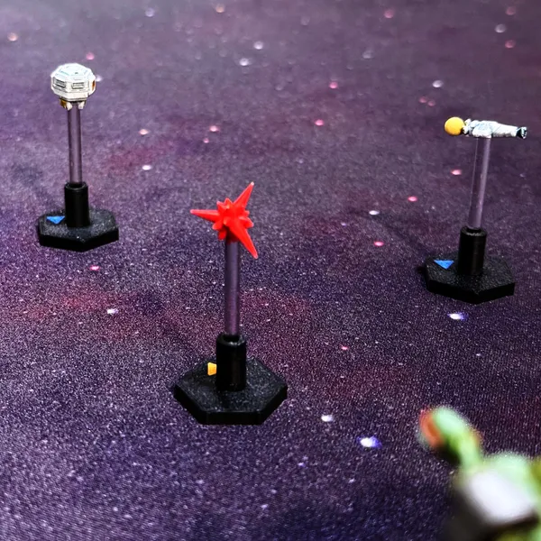 Painted probe, escape pod and torpedo tokens on clear stands and black hex bases against a purple starfield.