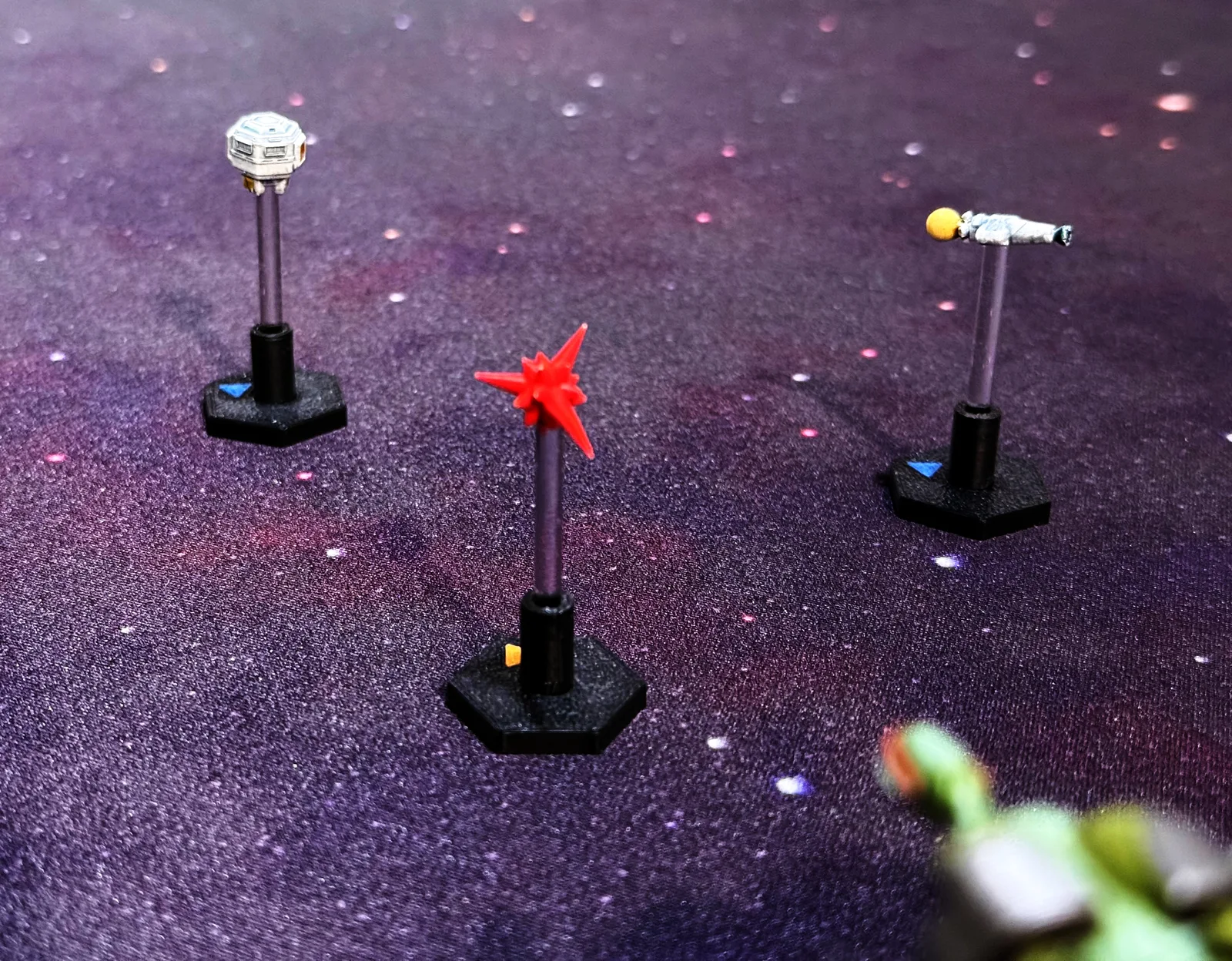 Painted probe, escape pod and torpedo tokens on clear stands and black hex bases against a purple starfield.
