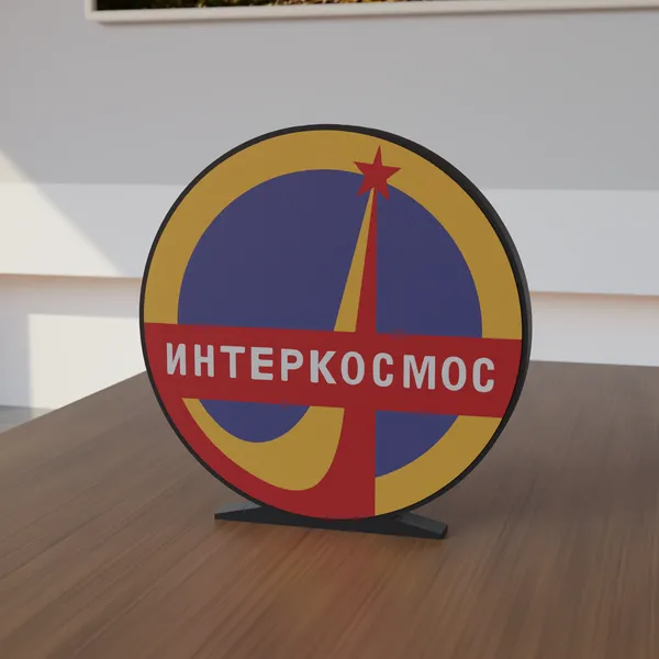 Freestanding 3D-printed logo sign, front view, 300mm size, standing on a wooden table.