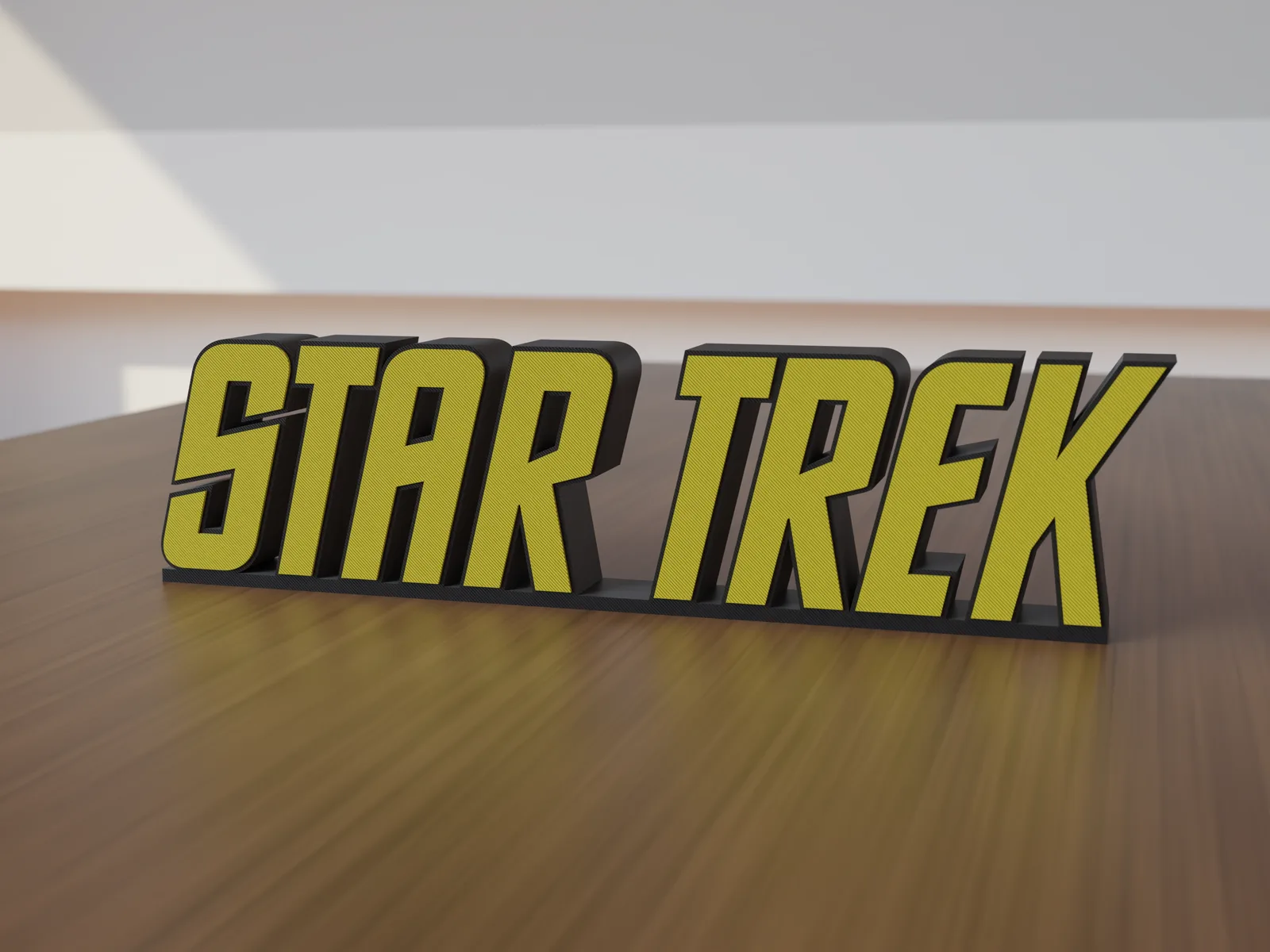 Freestanding 3D-printed logo sign, front view, yellow lettering on a black body, 300mm size, standing on a wooden table.