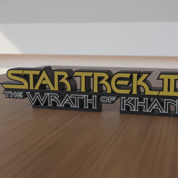Freestanding 3D-printed logo sign, front view, Black Face style with gold upper line and gray-outlined black letters below, 300mm size, standing on a wooden table.