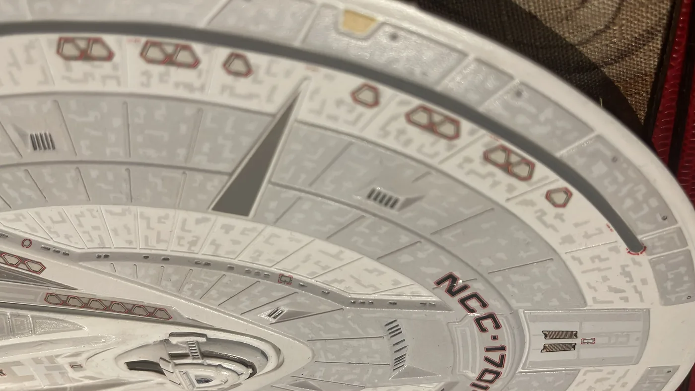 Close detail of a science-fiction starship model's upper saucer, showing panel lines, surface markings and the registry lettering.